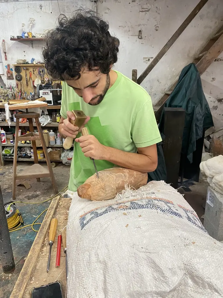 Alumno tallando una pieza de madera con gubia en el taller de escultura