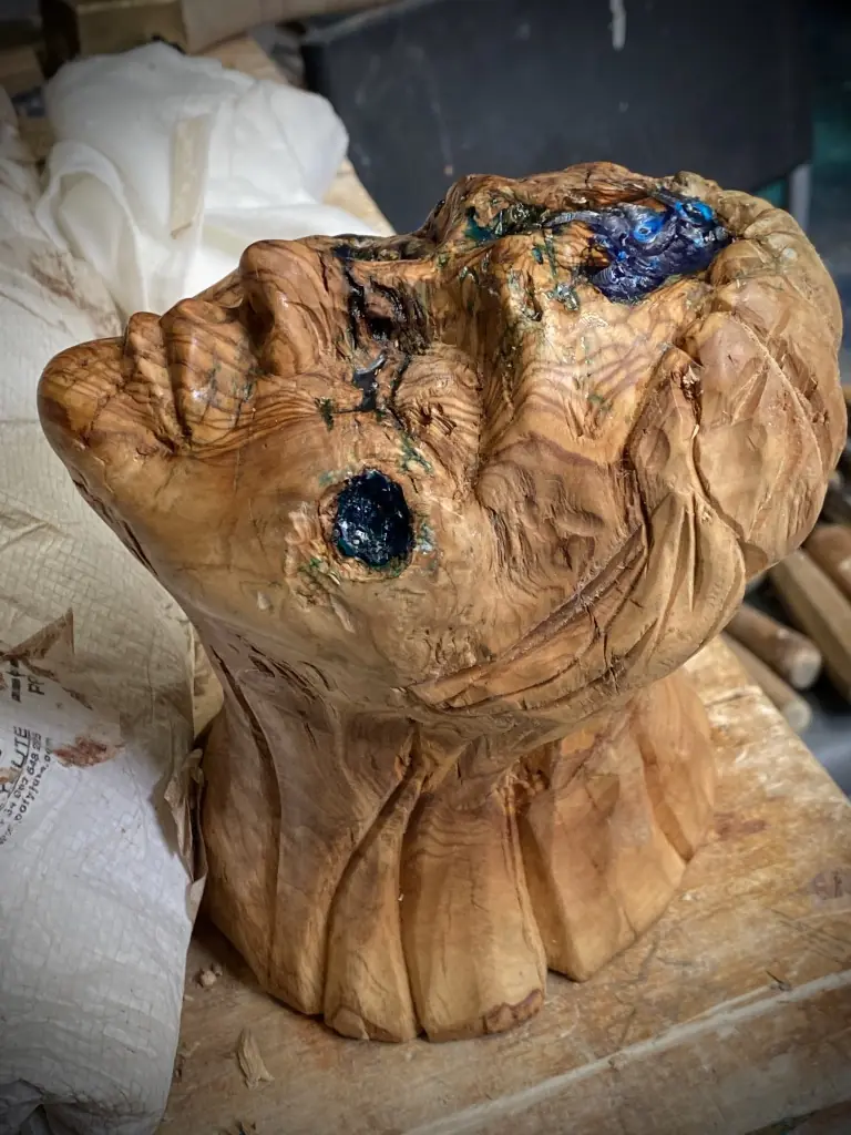 Rostro tallado en madera de olivo con incrustaciones de resina azul