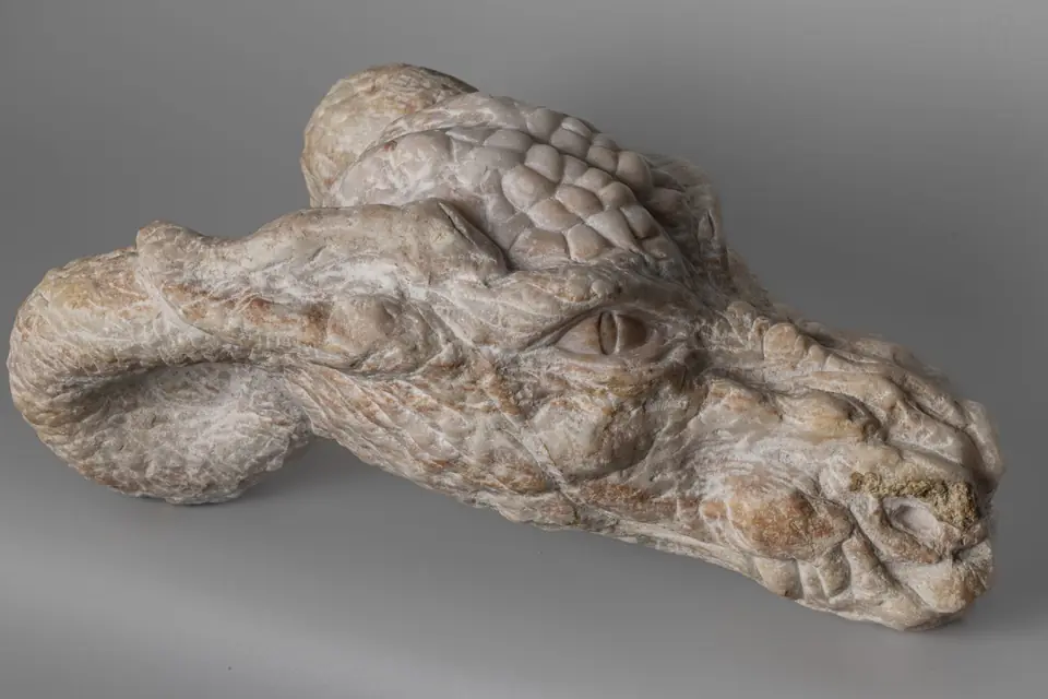 Escultura en piedra veteada con forma animal y textura de escamas