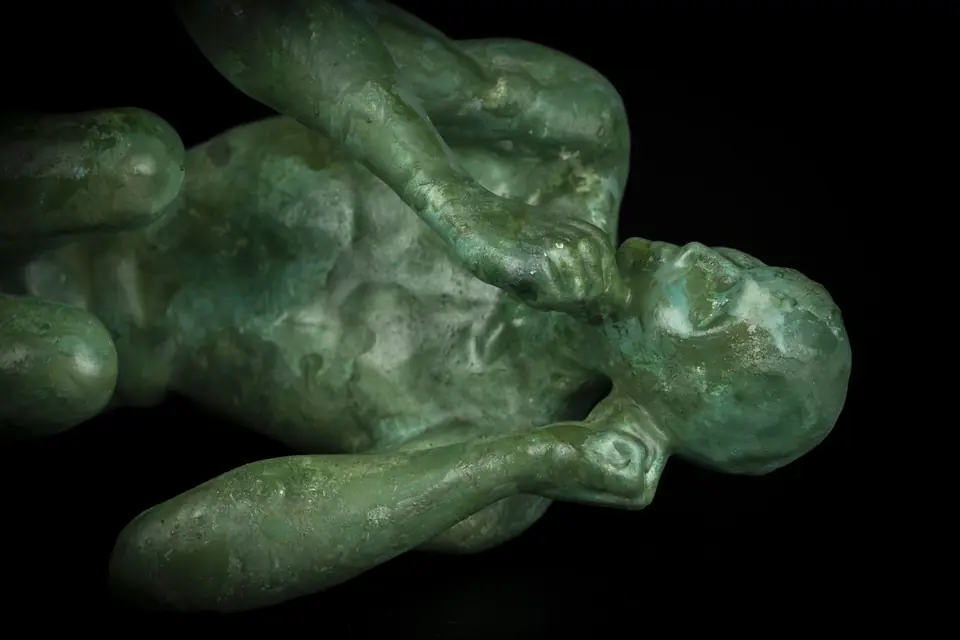 Escultura «Sumergido» de Marcos Domínguez: figura humana tendida con pátina verde bronce sobre fondo negro