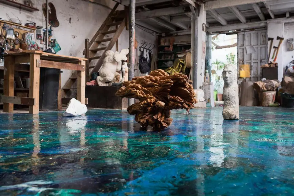 Interior del taller de escultura con suelo de resina azul, bancos de trabajo y esculturas en proceso